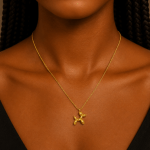 Gold balloon dog pendant necklace on a delicate cha